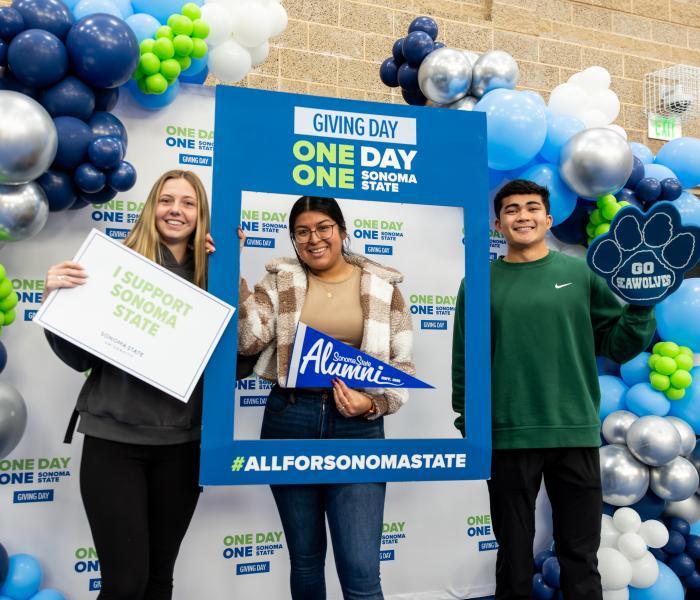 Three students holding signs i support sonoma state and go seawolves signs