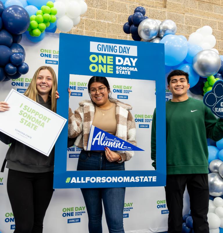 Three students holding signs i support sonoma state and go seawolves signs