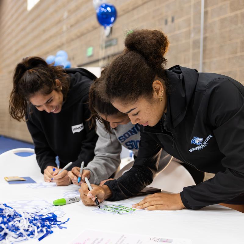 Two students signing a sign